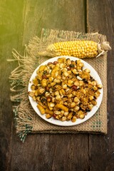 Spicy Corn or Maize Kernel in a Plate with Dry Corns on Wooden Background in Vertical Orientation