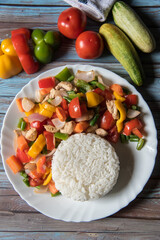 Vertical top view of rice with vegetables saute and meat in a white plate with ingredients 