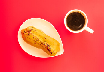 eclair and coffee on pink background.