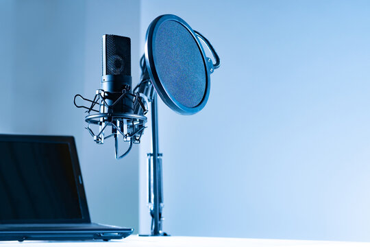 Condenser microphone with pop filter and vibration protection. Studio microphone on a gray background with space for text. Sound recording concept.