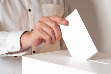 A man hand with a ballot paper. The hand puts the ballot in the slot of the box. Voting in elections. A man votes at a polling station. State elections. The national referendum.
