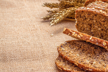 Rye bread isolated. Bakery with crusty loaves and crumbs. Fresh loaf of rustic traditional bread with wheat grain ear or spike plant on natural cotton background. Bio ingredients, healthy with seeds.