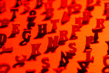 Black and red background from the letters of the English alphabet. Background of Latin letters in focus in the center. Latin letters are placed on the table in any order. Getting an education.