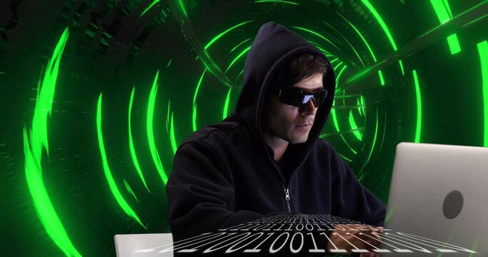Male hacker using laptop against glowing green tunnel