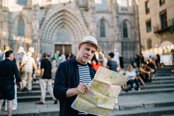 Focused mature male tourist reading map