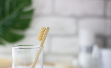 Wooden toothbrush on a blurry bathroom background. Freshness, drops of water on the glass.