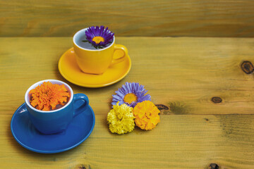 Beautiful flower petals in a cups  on wooden background.
