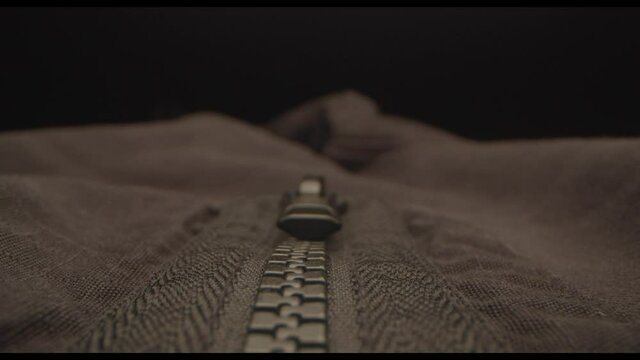 Moving probe lens shot along the zip of a black jacket.