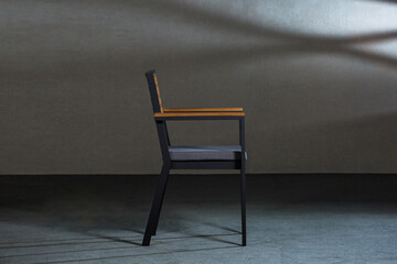 Closeup of a simple modern chair with metallic legs in a room with gray walls