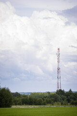 A telecommunications tower with radio and satellite dishes is installed in a rural area on a green...