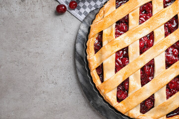 Delicious fresh pie and cherries on grey table, flat lay. Space for text