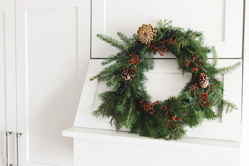 Rustic christmas wreath hanging on modern kitchen hood, festive holiday decoration.