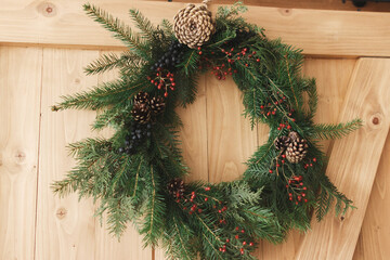 Rustic christmas wreath on wooden door indoors, festive holiday decoration