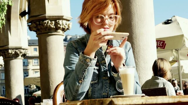Beautiful woman taking photo of tasty drink with cellphone in cafe in the city, 4K
