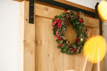 Christmas wreath hanging on rustic wooden door in house.