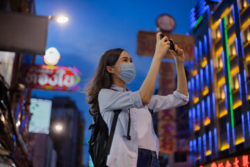 Traveler women wear the mask  using smartphone to take a photo in chinatown.