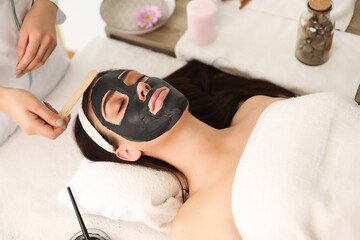 Obraz na płótnie Canvas Face peeling mask, spa beauty treatment, skincare. Woman getting facial care by beautician at spa salon, side view, close-up