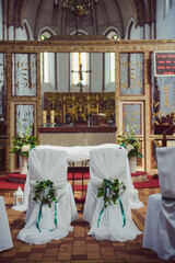 Church sanctuary before a wedding ceremony. Empty chairs for bride and groom.