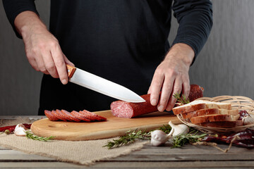 Man cuts a sausage for a sandwich.