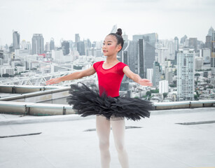 Ballet girl students show jumping skills while performing outdoors on a high-rise building.