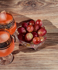 Grapes in a crystal vase with a glass of ice drink on a wooden background.