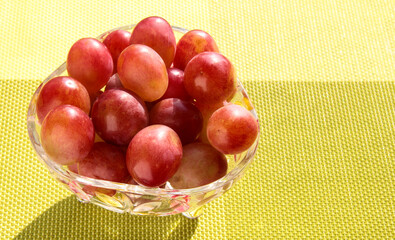 Grapes in a crystal vase on a bright green background.