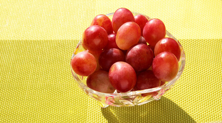 Grapes in a crystal vase on a bright green background.