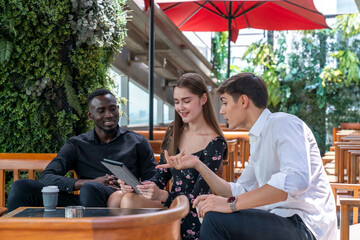 Multiracial colleagues have fun at coffee breaks in a public place. Group of diverse multiethnic businesspeople discussing their project in the coffee lounge. Concept of workplace gender equality. 