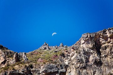 Low angle view of half moon over a rocky mountain, Chivay, Arequipa, Peru
