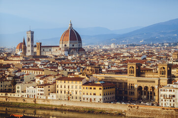 Fototapeta premium Sunset winter panorama of Florence, Italy, in golden sunlight, with the Arno river and the dome of the cathedral of Santa Maria del Fiore