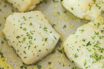 Close-up of some hake loins in green sauce with parsley and oil. Healthy food and fish.