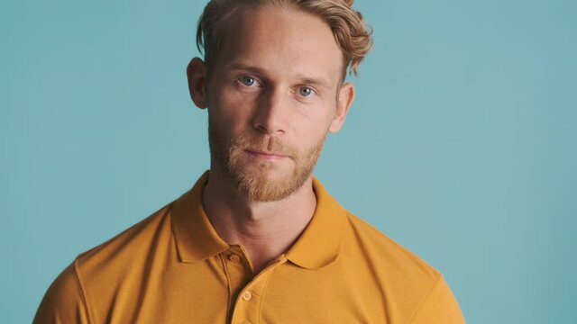 Handsome blond bearded man confidently posing on camera over colorful background