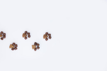 Dry cat food in the shape of paws on a white background.flat lay.copy space.Pet store poster design.The concept of proper nutrition for Pets.Minimalistic pattern