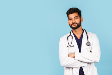 Fototapeta premium Handsome modern Indian / Asian doctor with stethoscope, in uniform on blue background