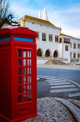 Main square of the town of Sintra, near Lisbon (Portugal), with a red classic pay phone booth and the exterior facade of the National Palace, famous landmark