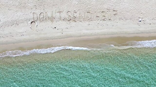 Sand beach by the blue sea with Don't sand help SOS message. Aerial view 