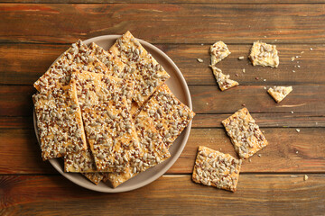 Delicious crispy crackers on wooden table, flat lay