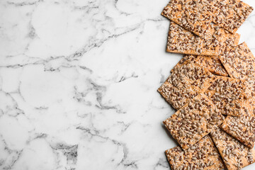 Many delicious crackers on white marble table, flat lay. Space for text