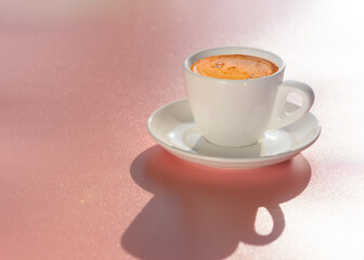 White cup of coffee on light pink background in natural soft morning sunlight. Pink mood. Copy space.