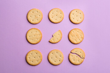 Delicious crackers on violet background, flat lay