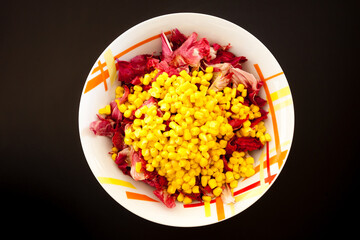 Salad with corn on black table, top view