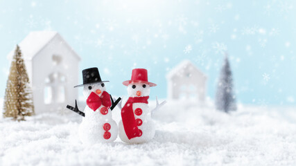 A couple of snowmen standing in snow over winter background.