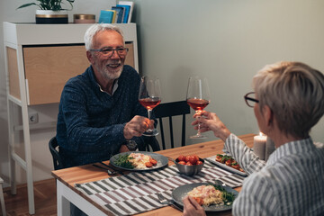 Happy senior couple toasting at dining table stock photo