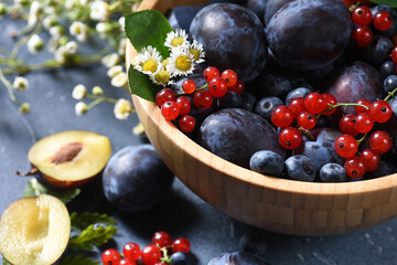 Ripe summer berries in a wooden bowl on a dark background