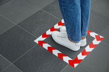 Woman standing on taped floor marking for social distance, closeup. Coronavirus pandemic