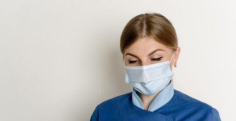 Close up of woman wearing medical face mask on teal background