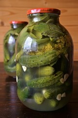 Glass jars with pickles, dill and garlic in glass jar on wooden table