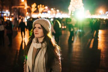 red-haired young woman stands on the street in the evening of new year and christmas waiting for...
