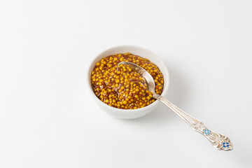French dijon grain mustard sauce in a small white bowl on a white background