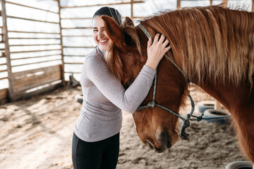 
young woman hugs brown horse and laughs
